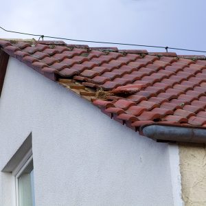 Home roof damage after storm. fallen shingles on house